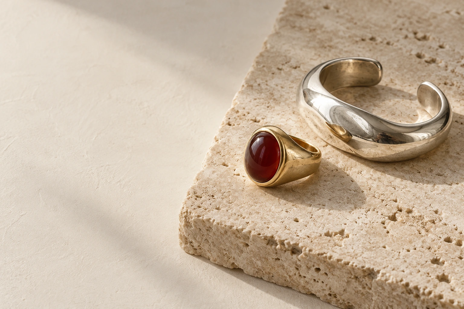 Minimalist gold aqeeq ring and sculptural silver cuff on pale stone